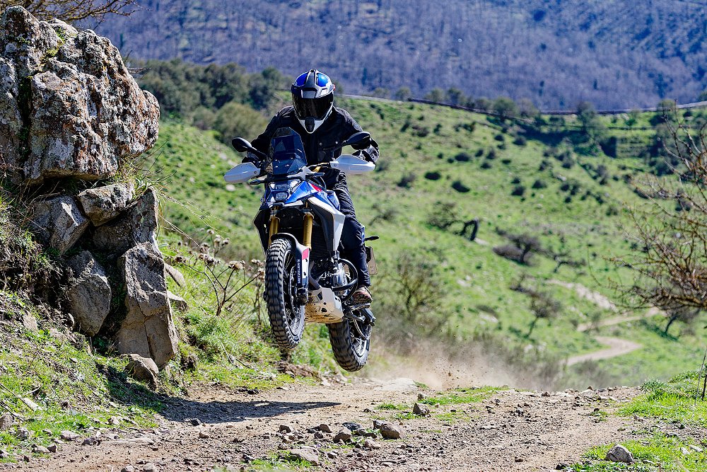 A rider launches the F 450 GS off a jump while trail riding.