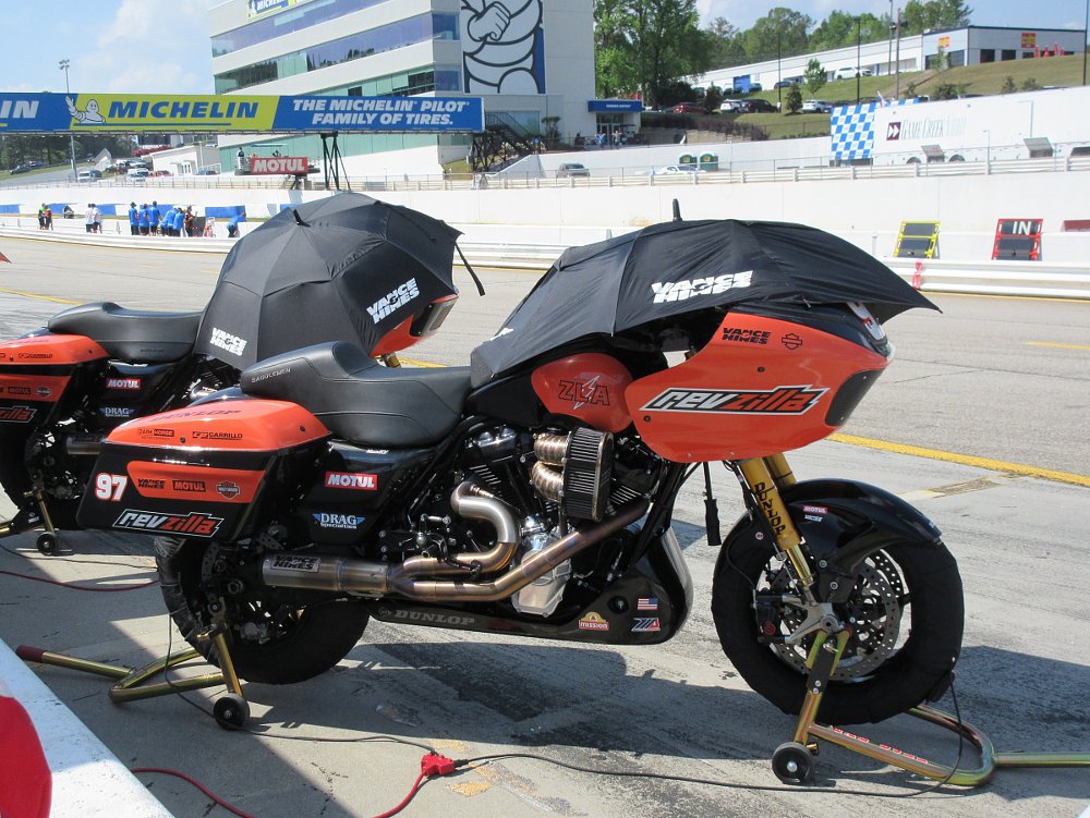 two orange Harley-Davidson Road Glide race bikes with RevZilla branding waiting on pit lane before a race at Road Atlanta