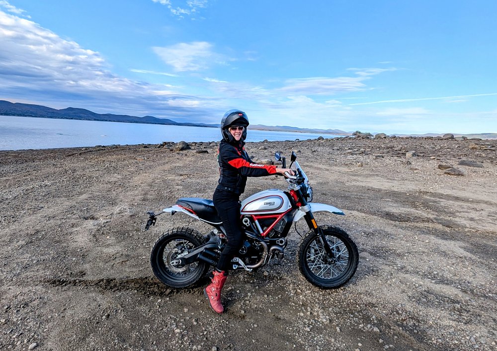 the author in black and red gear on her silver and red Desert Sled on the dirt beside a large lake