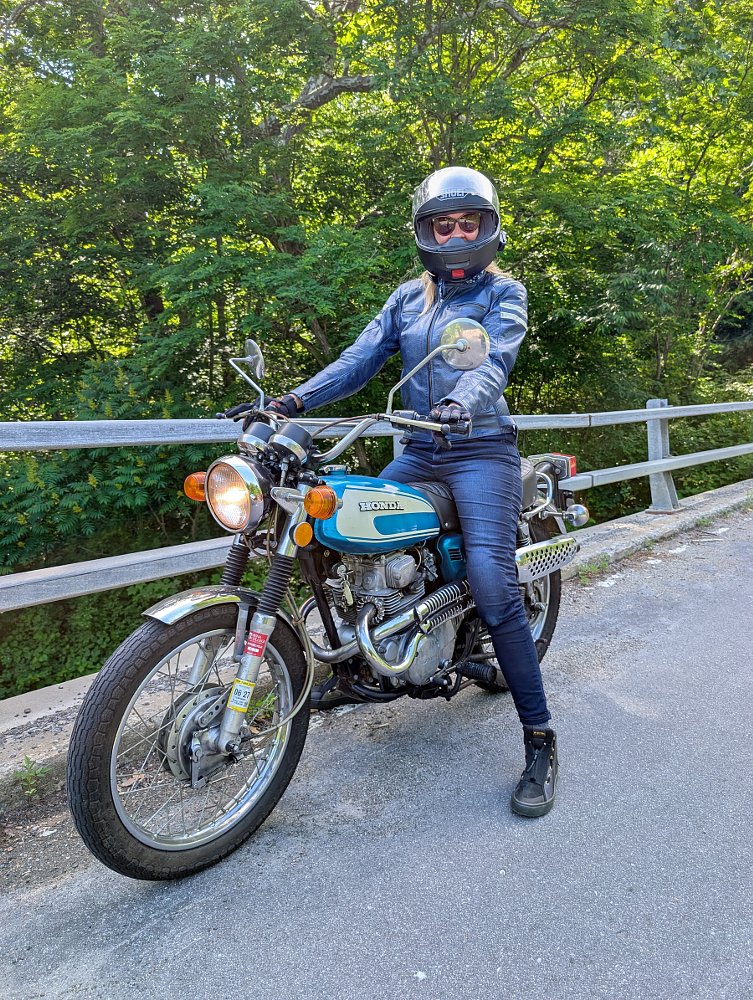 the author in a blue leather jacket and helmet sitting on her blue vintage CL200 Scrambler