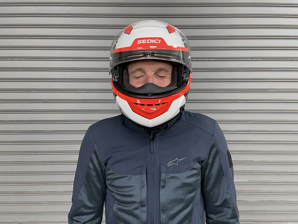 Rider sneezing while wearing a motorcycle helmet. 