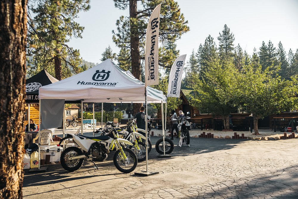 The husqvarna pop up and pit area adorned with demo husqvarna motorcycles in the cabins and pine trees of the Outpost resort.