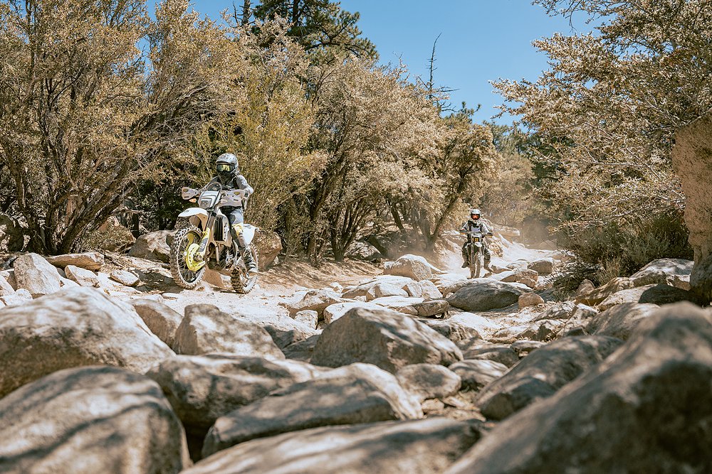 A group of female riders pilot their motorcycles through a rocky trail.