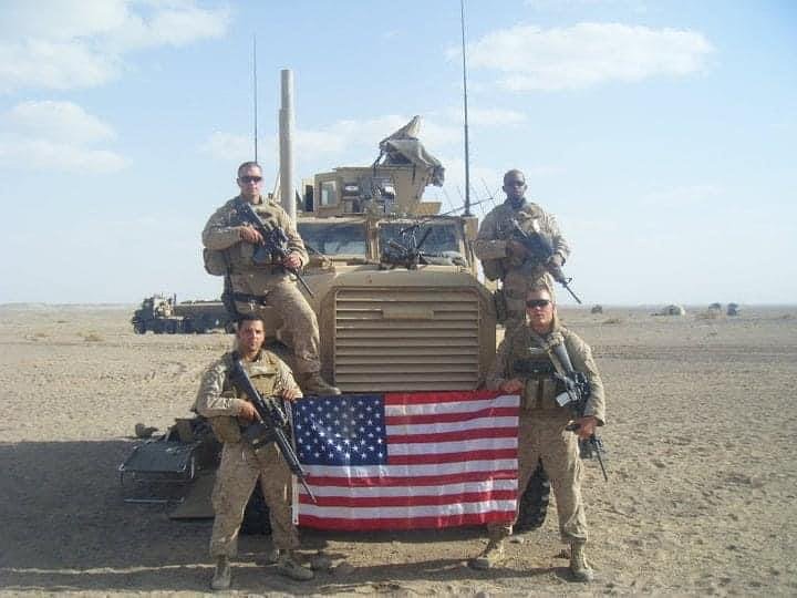 Marine soldiers posing with a humvee truck in Afghanistan.