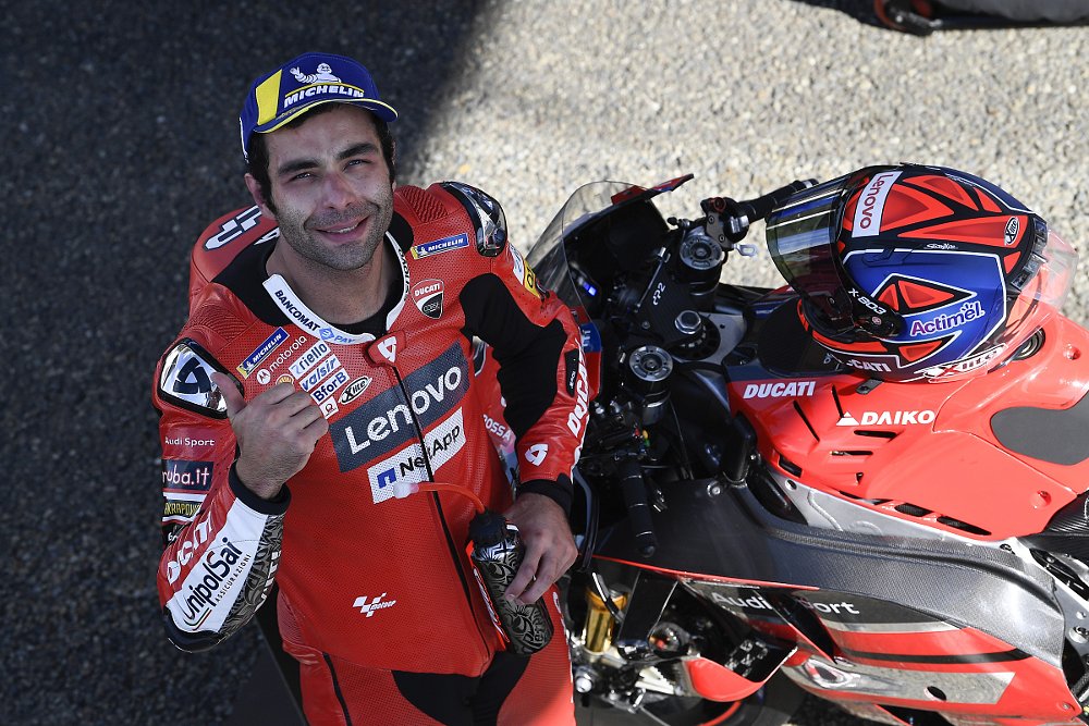 Danilo Petrucci smiling beside his Ducati MotoGP motorcycle