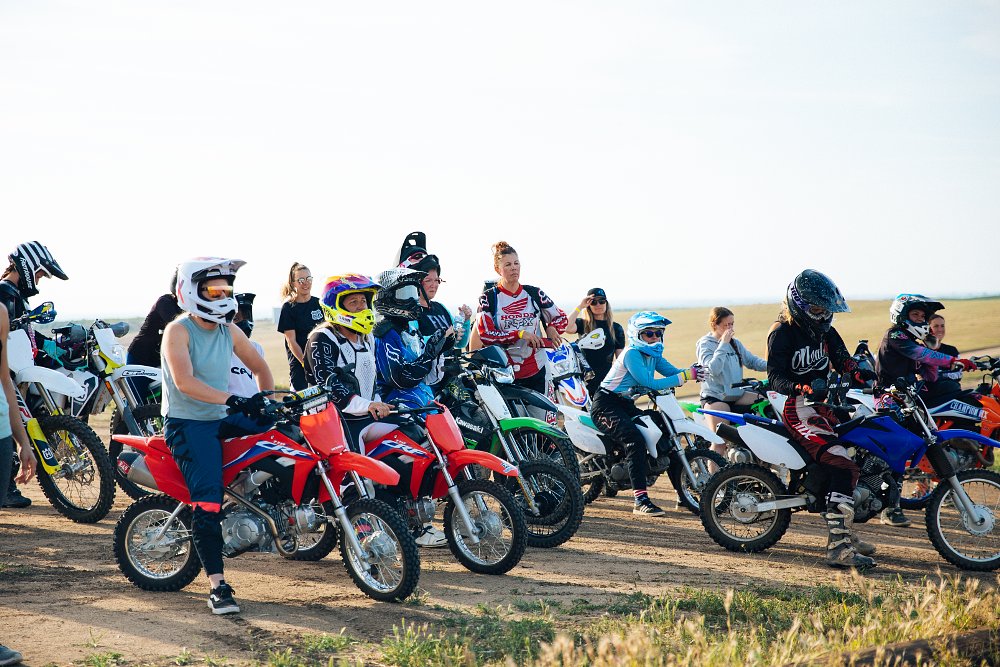 A group of women riders on mini dirtbikes gather around before riding