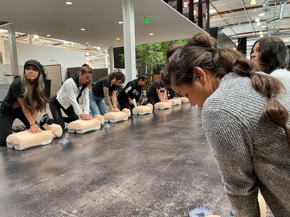 A group of students gather around CPR mannequins to learn the basics of CPR