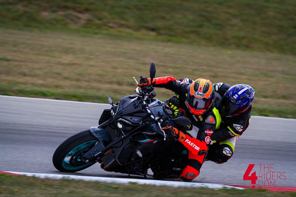 A rider coach has a student on the back of the motorcycle to ride a lap around the track