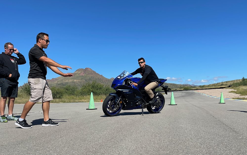 A YCRS rider coach explains a technique while a rider on the motorcycle demonstrates