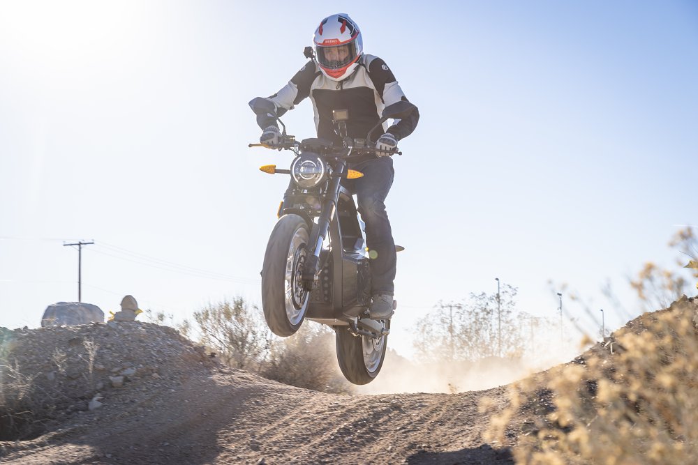 A Sondors MetaCycle jumping over a dirt bump, toward camera