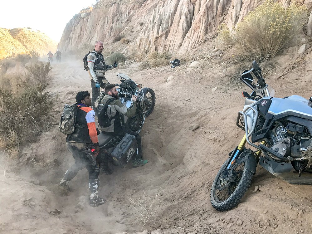 two motorcycles crashed on their sides in a hole on the trail