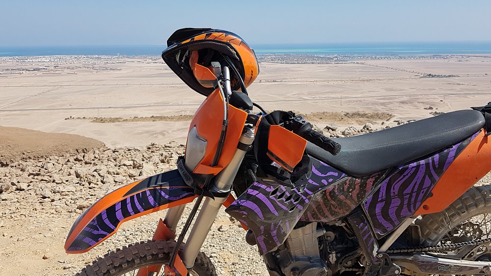 dirt bike parked in the desert near the sea