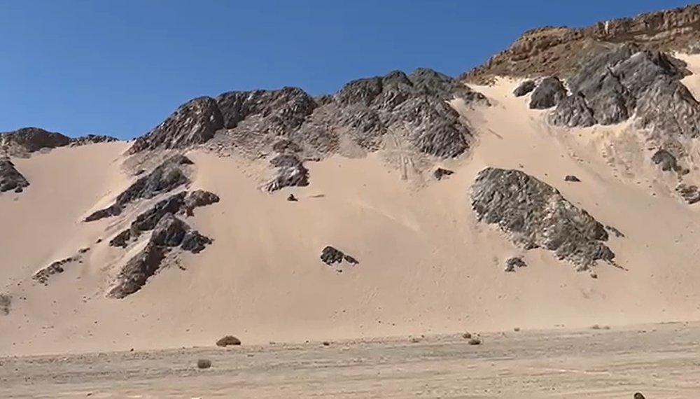 dirt bike arcing up a distant dune