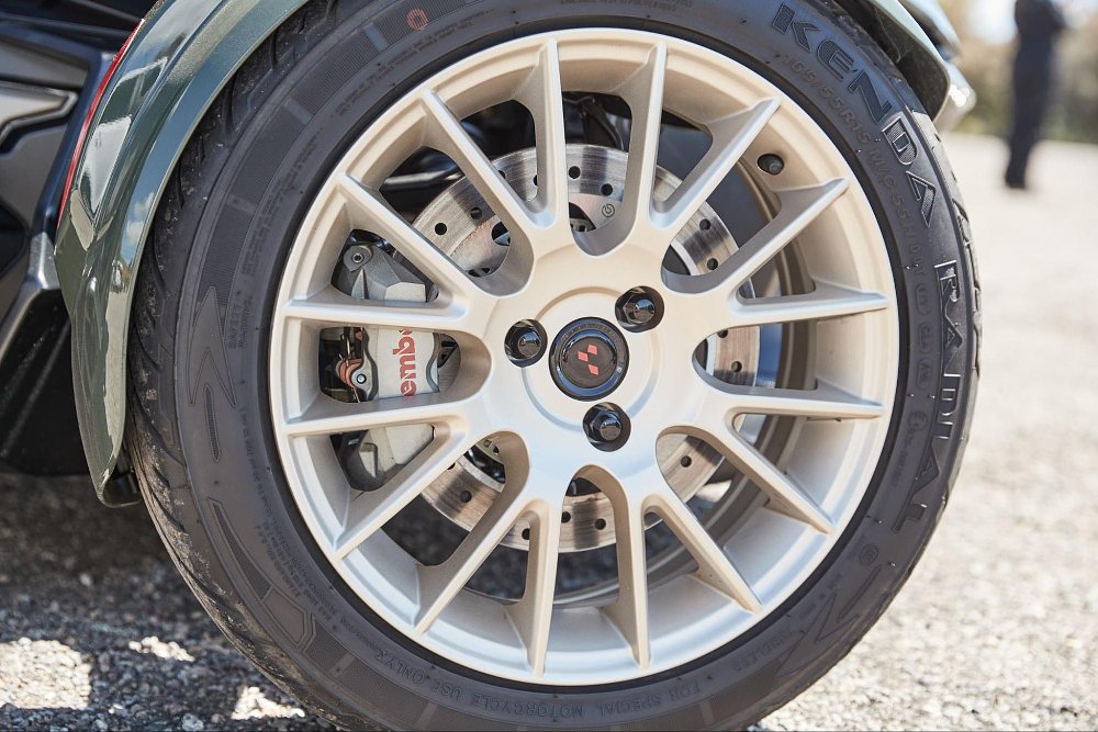 a close up of a front tire of the can-am with tan colored rims and brembo brakes