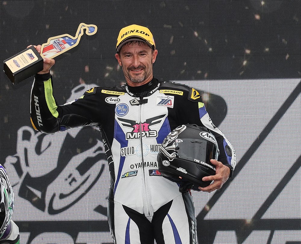 Josh Hayes holding the winner's trophy on the podium at NJMP