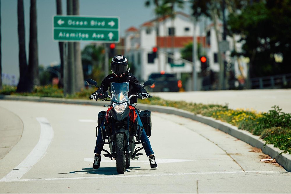 A short rider is on their tip toes at a stop light riding the RX1E