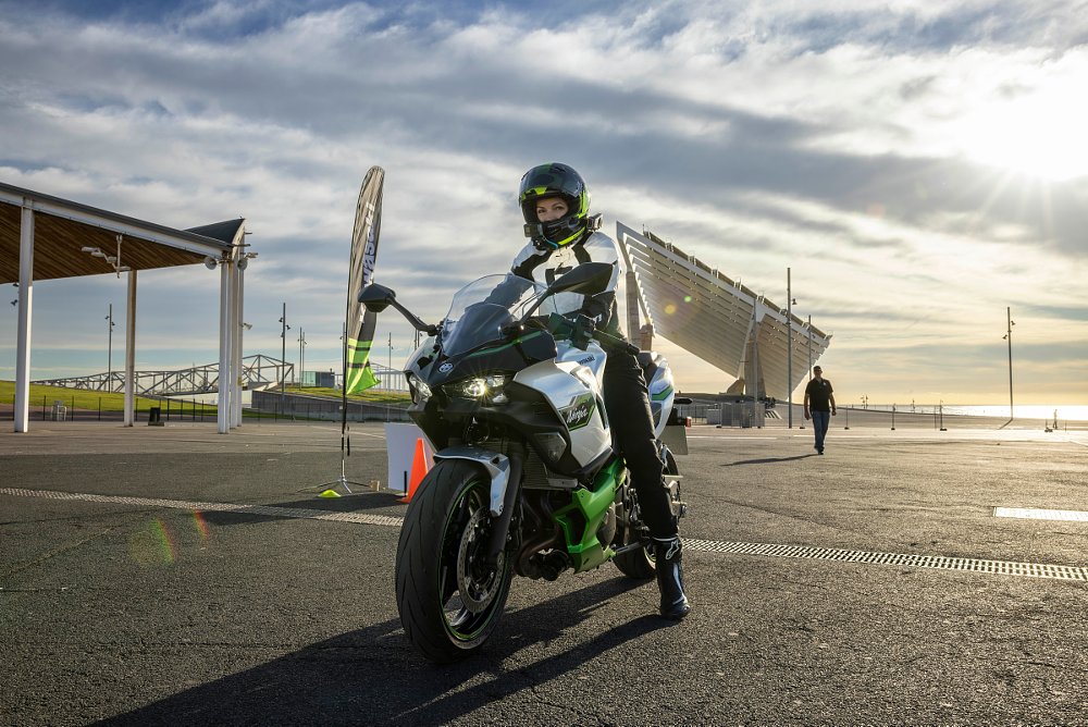 A female rider comes to a stop in a parking lot on the ninja 7 hybrid