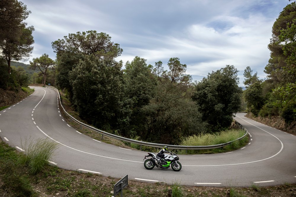 a far away shot of the ninja 7 hybrid riding through a hairpin turn on a cliffside road