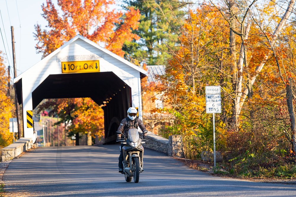 Transalp riding out of a rural covered bridge