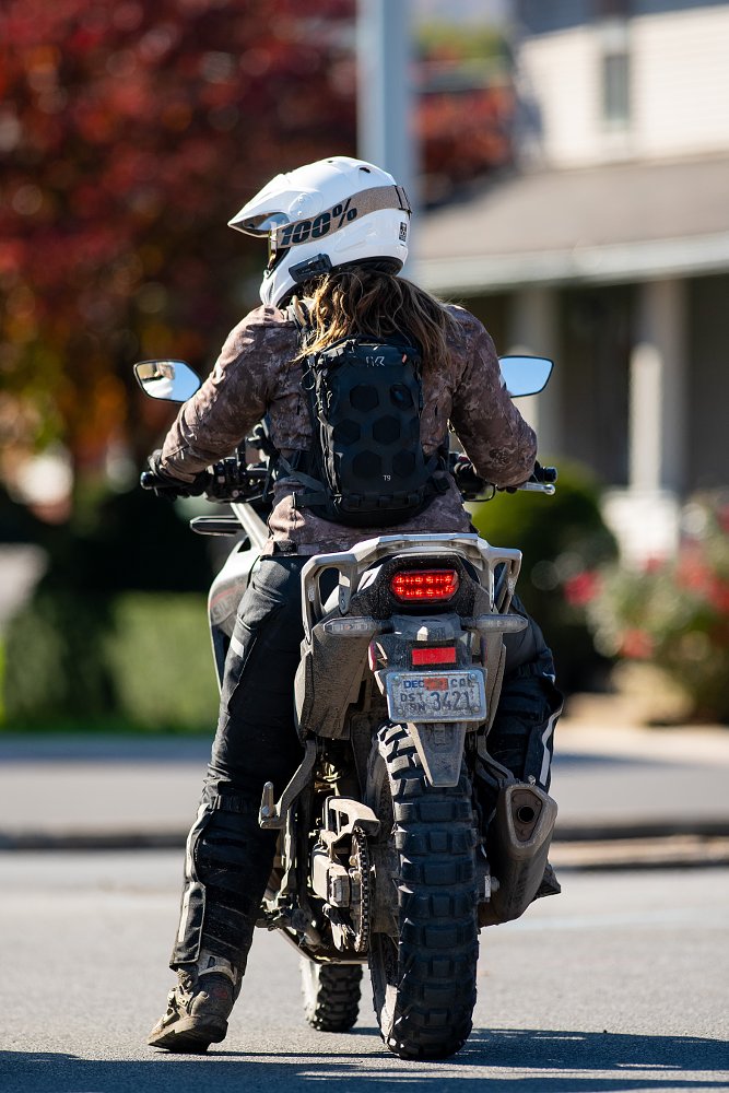 view of the motorcycle and the writer on board from behind, showing her left foot on the ground