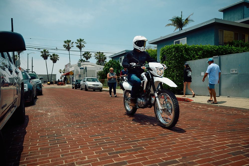 rider on a Honda XR150L on a residential street near the beach