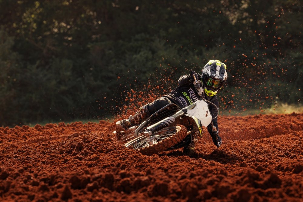 rider leaned over on the Triumph MX bike on a race course