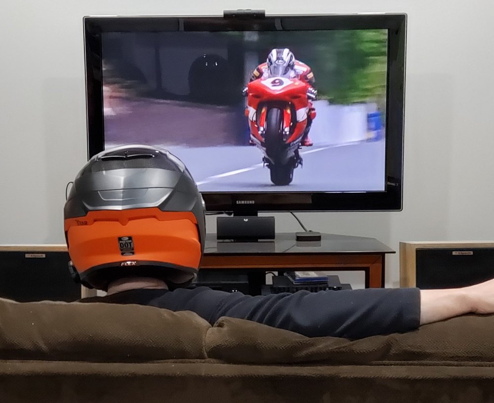 person wearing a helmet and watching a motorcycle race on TV