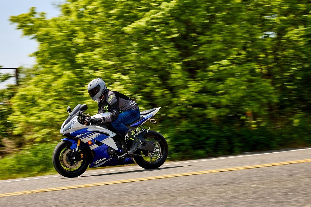 A blue yamaha sportbike whizzes by camera with speed blurring on background