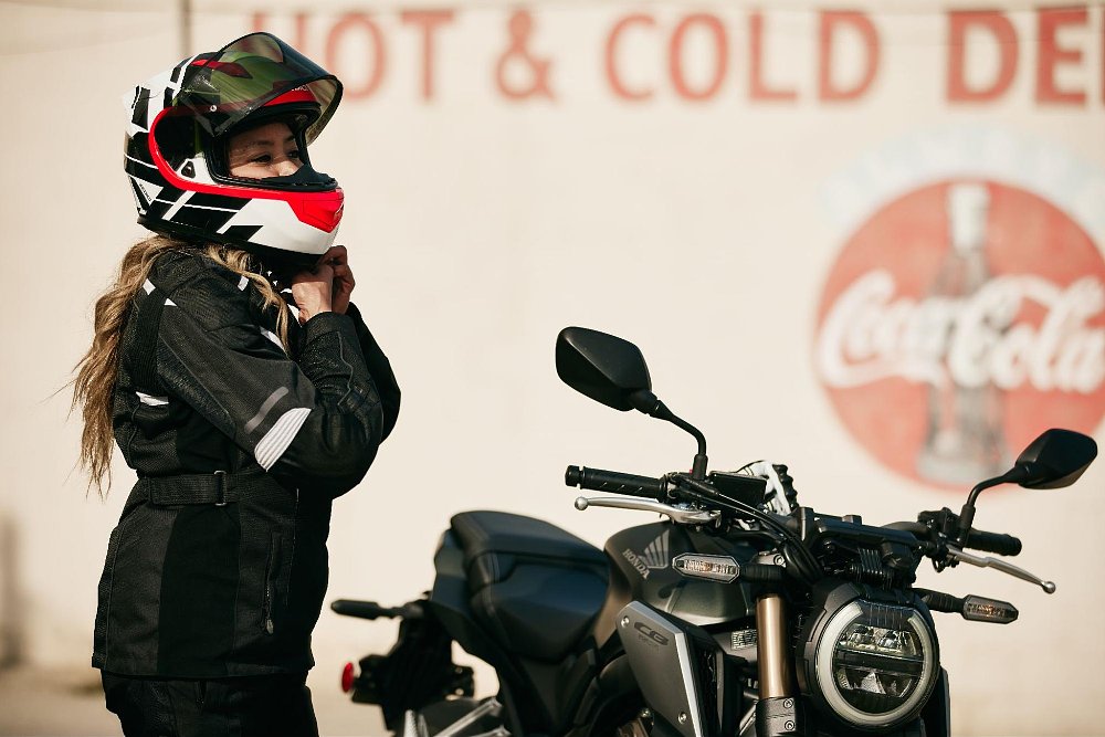 A female rider straps on a helmet before riding
