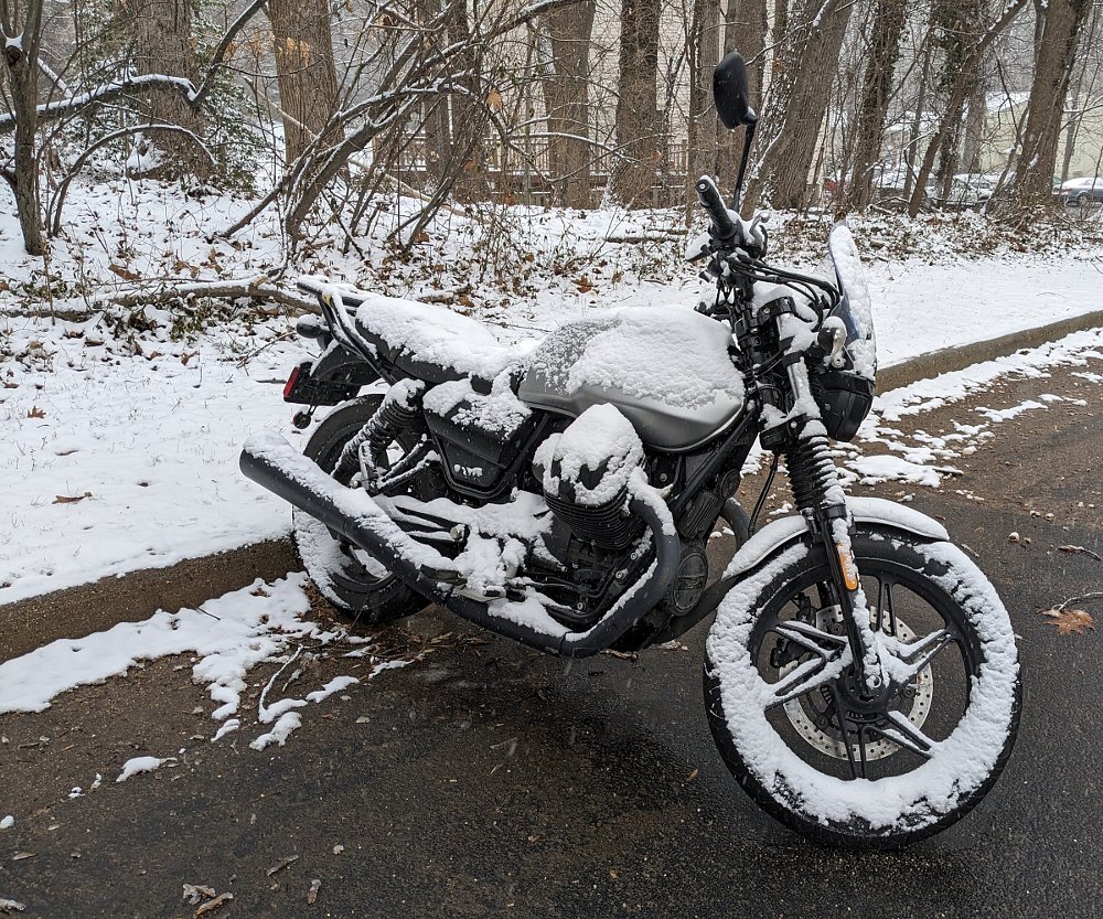 the Moto Guzzi V7 partially covered in snow in a parking lot