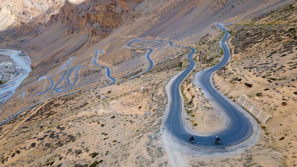 distant view of motorcycles on hairpin turns on a mountain road in India