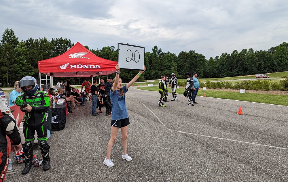 Mikayla holds up a large whiteboard serving as a pit board