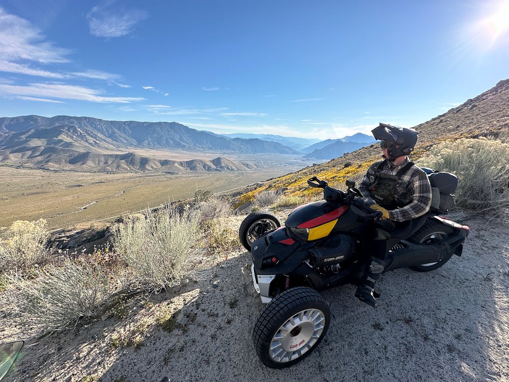 A Can-Am Ryker Rally stopped on the side of a dirt road overlooking a valley.