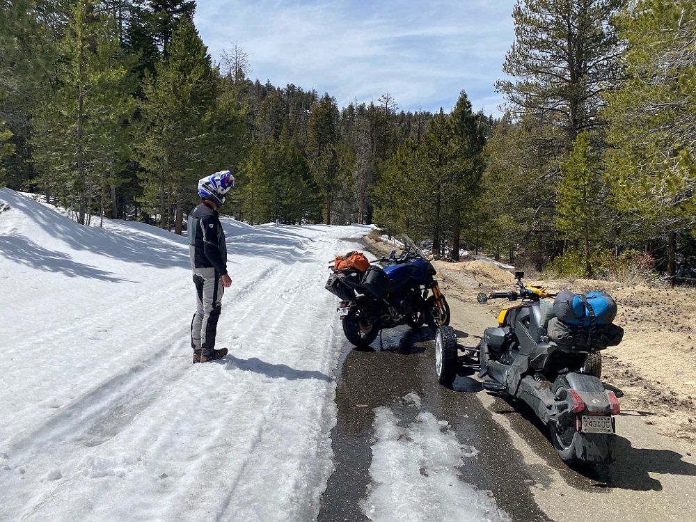 A Can-Am Ryker Rally and Yamaha NIKEN on a paved road nearly covered in snow.