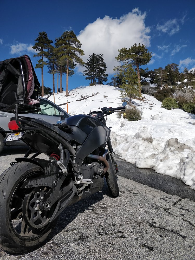 Buell loaded with luggage by the side of the road with a large snow bank in the background