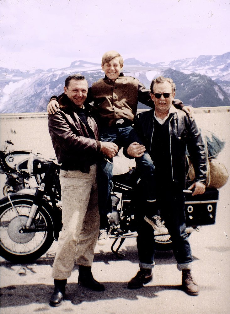 the two men holding the young boy between them in front of the motorcycle