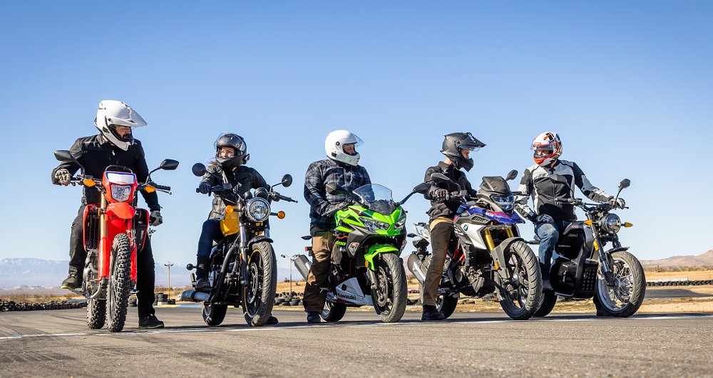 five riders on small motorcycles lined up side by side for a test run