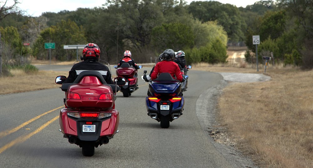 rear view of several Gold Wings on the road in a group, with the one on the left looking larger