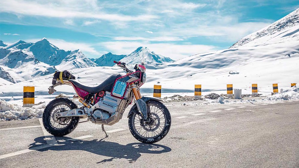 Royal Enfield's Electric Himalayan prototype sits at the base of snow-covered mountains. 