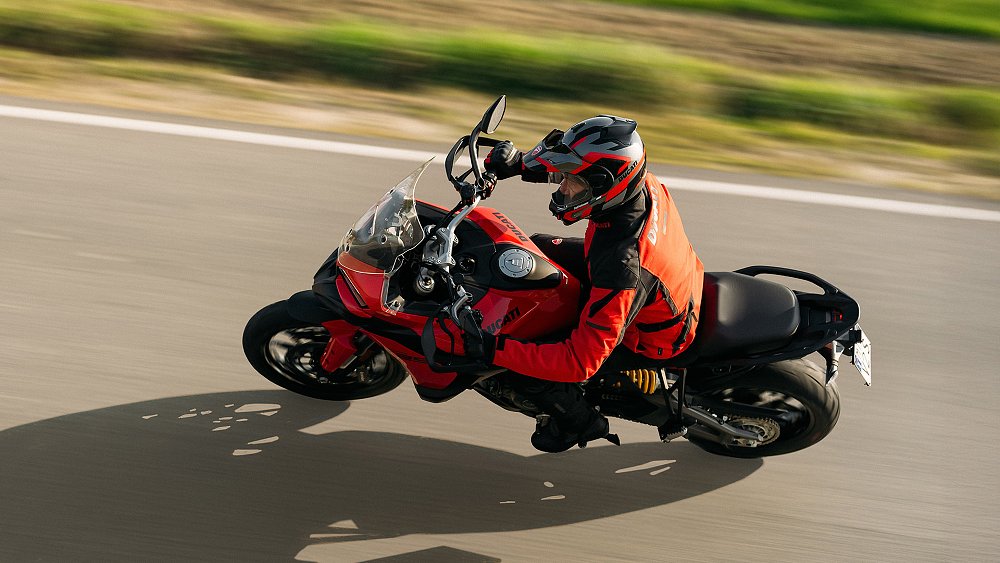 With the background blurred, a touring rider pilots the 2025 Ducati Multistrada V2 S through a curve.