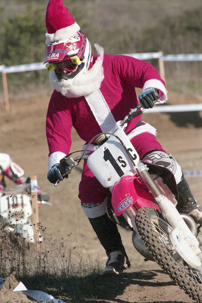 racer in a corner on a motocross track wearing a full Santa Claus suit