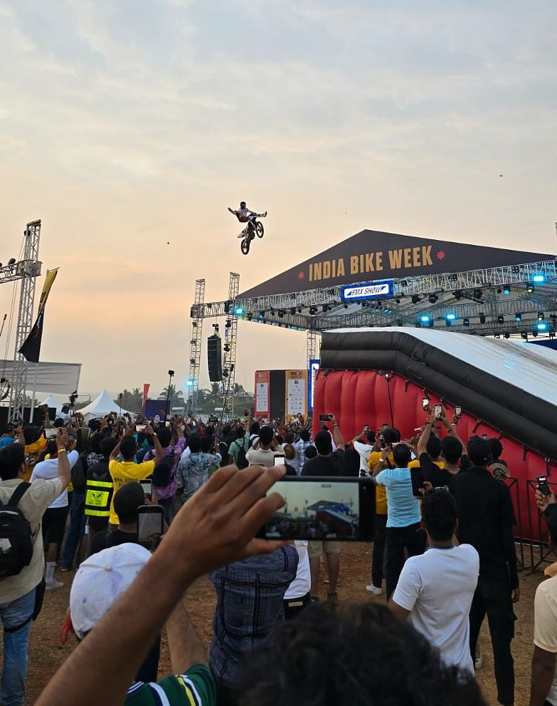 stunt rider flying through the air on his motorcycle next to India Bike Week sign