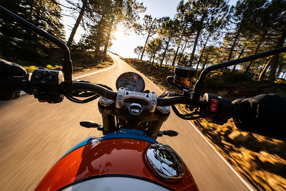 Taken from the rider's perspective, the Speed Twin 900 weaves through a twisty mountain road.