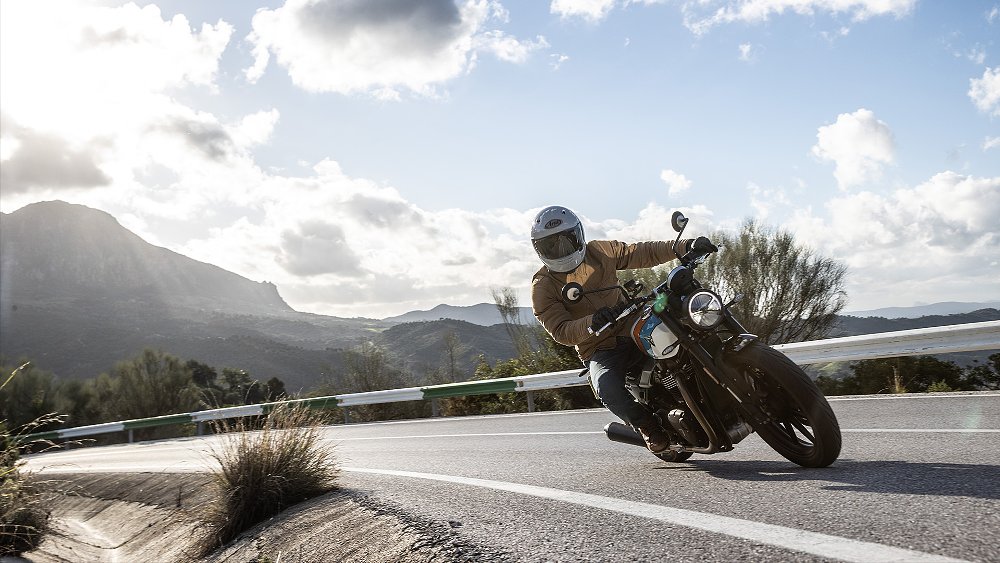 Dustin rides the Speed Twin 900 through a sweeper with mountain peak in the background.