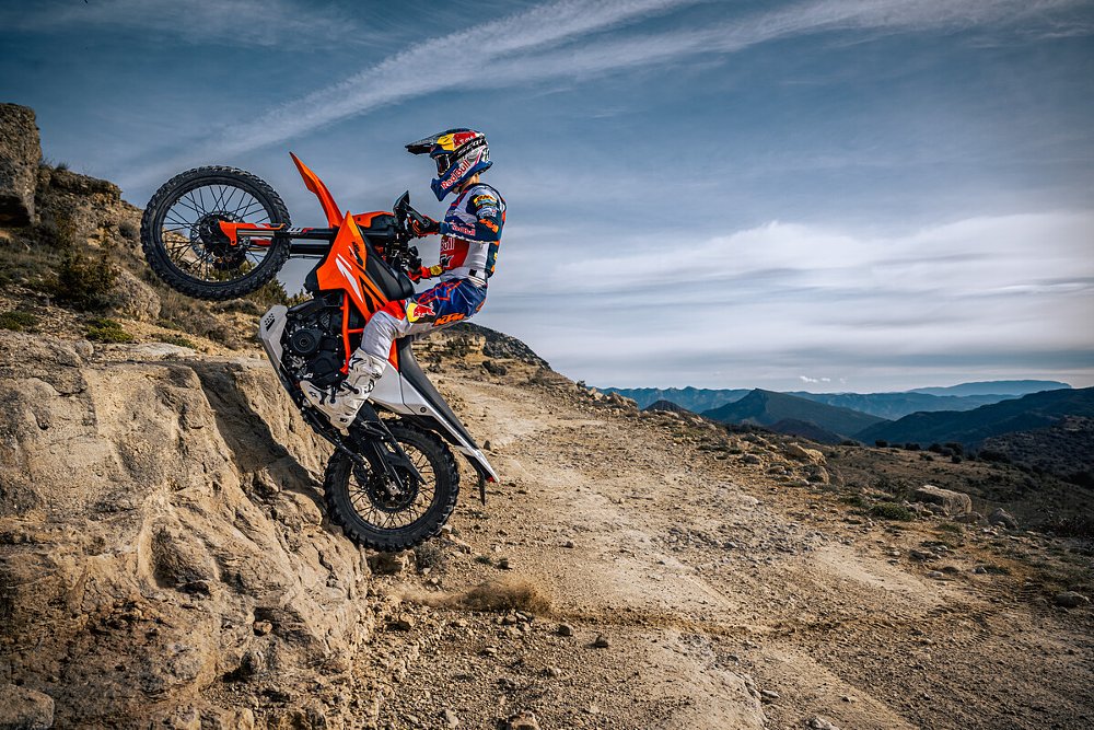 A 390 Enduro R rider jumping the bike up a rock ledge.