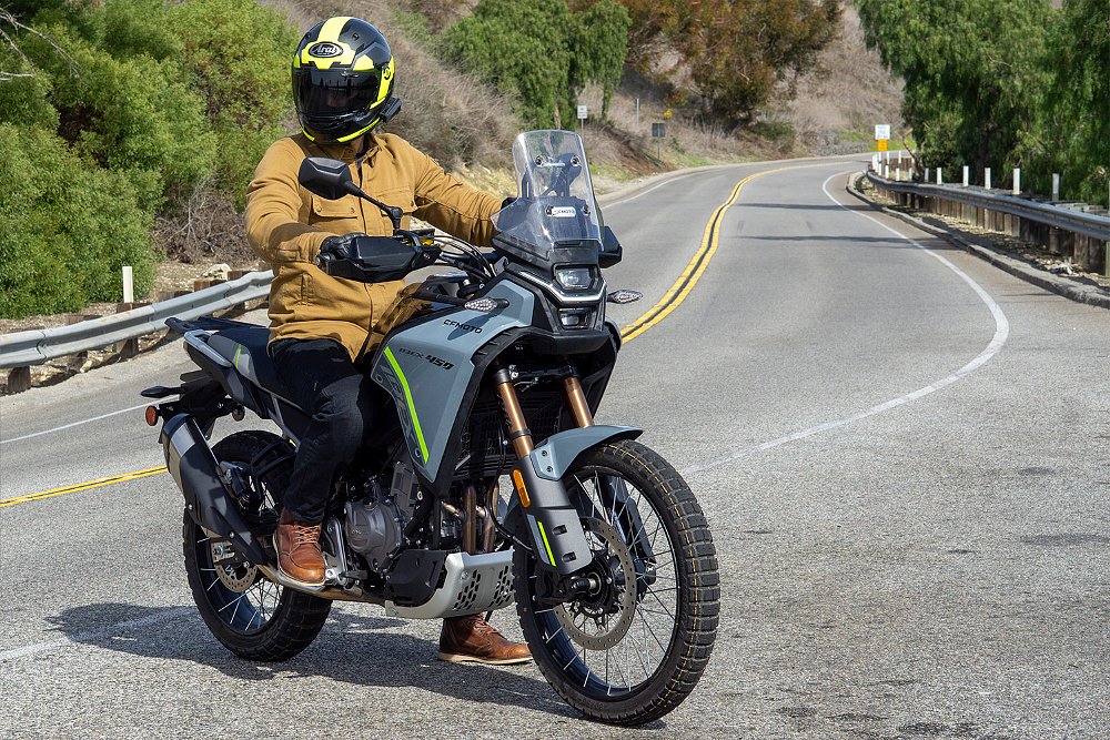Dustin mounted on the CFMOTO Ibex 450 alongside a canyon road.