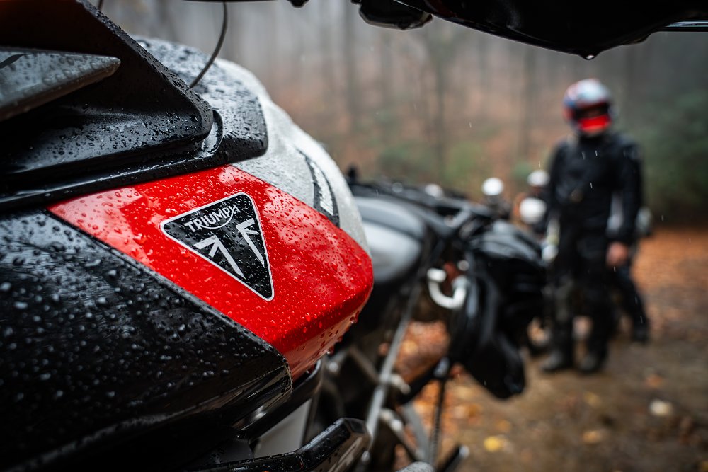 A close-up of rain droplets collecting on the gas tank of a Triumph Tiger 900 Rally Pro.