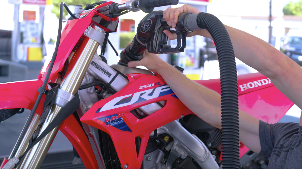 Motorcycle in the back of a truck getting gassed up.