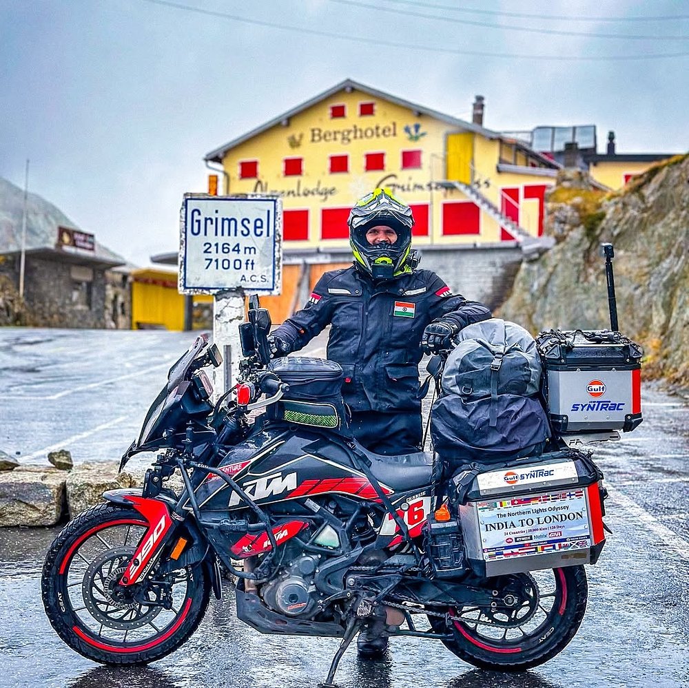 the fully loaded KTM at a sign marking more than 7,000 feet in altitude in the mountains