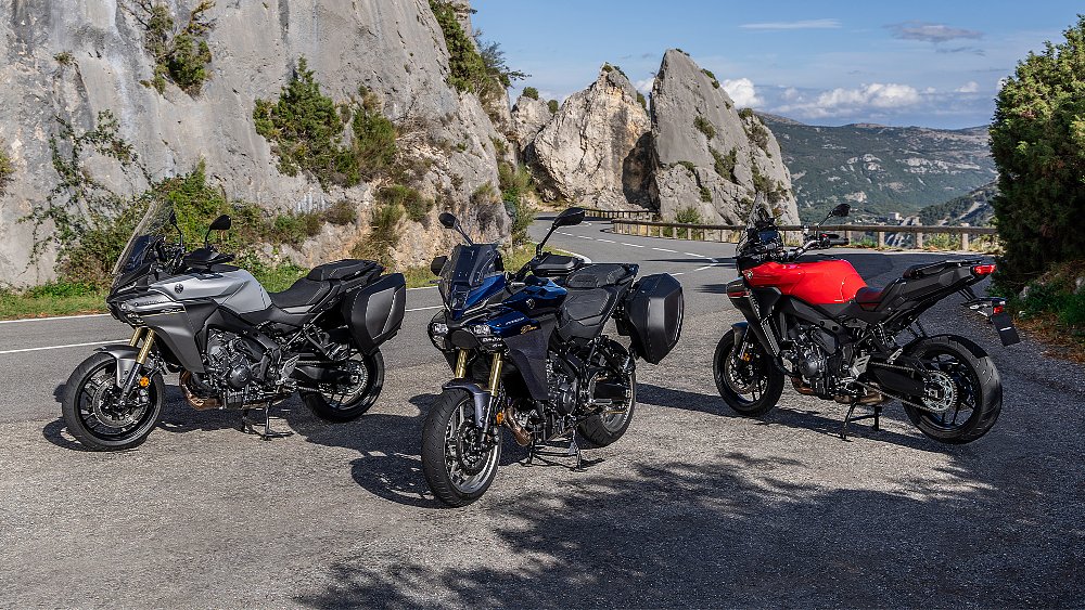 Three European Yamaha Tracer 9 models staged alongside a curvy road.
